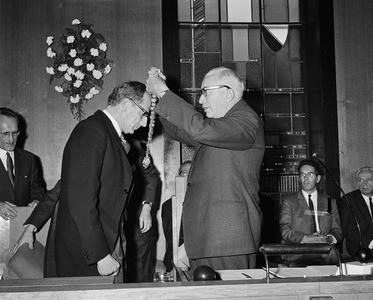 102082 Afbeelding van het omhangen van de ambtsketen tijdens de installatie van burgemeester H.G.I. baron van Tuyll van ...